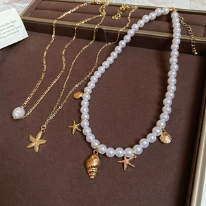 Macro shot of layered necklaces with gold starfish, seashell charms and white pearls
