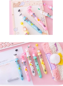 Detail of multi-color cartoon ballpoint pens with 3D silicone animal toppers on a pink desk