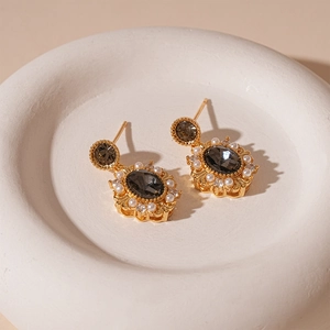 Detailed close-up of vintage oval grey gemstone earrings with pearls in a ceramic tray