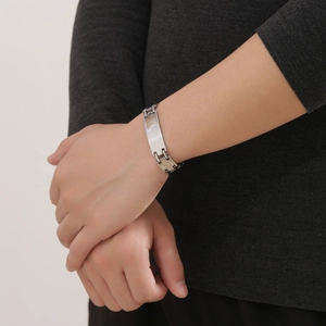 Close-up of a men's silver titanium steel chain bracelet with a smooth polished nameplate