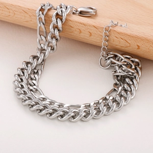 Detail of silver stainless steel Cuban link chain bracelet with lobster clasp on wood