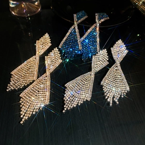 Macro shot of long fringe rhinestone earrings in gold, blue and silver on black background