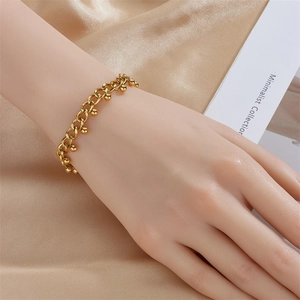 Minimalist gold beaded chain bracelet for women on a silky fabric background
