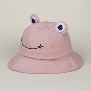 Detail of cute pink frog bucket hat showing 3D eyes and embroidered smile on cotton fabric