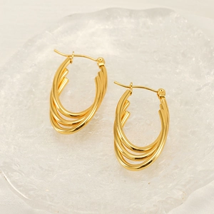 Triple layered gold stainless steel oval hoop earrings on elegant textured glass tray