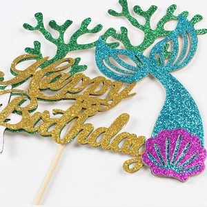 Macro view of mermaid cake toppers with glitter gold Happy Birthday text and sea shells