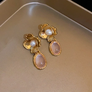 Gros plan de boucles d'oreilles vintage en résine avec perle blanche et gemme rose dorée