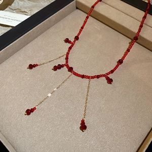 Detailed macro view of red crystal beaded tassel necklace with gold-toned chains