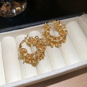 Boucles d'oreilles créoles torsadées plaquées or avec zircons sur une boîte en velours blanc