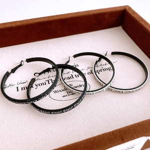 Macro shot of minimalist round hoop earrings with black and white enamel ENIC lettering