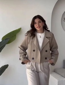 Detail of khaki short trench coat featuring double-breasted buttons and notched lapels