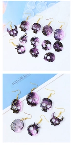Macro view of skull earrings with purple nebula resin texture and gold glitter details