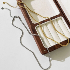 Minimalist gold and silver titanium steel snowflake chains displayed on a wooden jewelry box