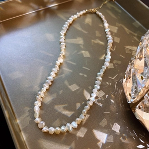 Elegant baroque freshwater pearl necklace with gold clasp on a luxury golden tray