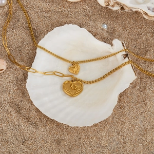 Close-up of golden double-layer heart necklaces on a shell and sandy beach background