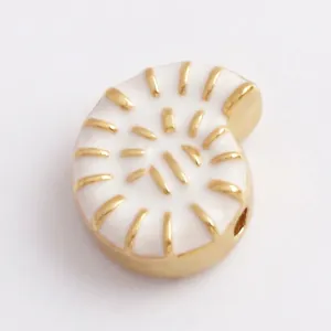 Detailed view of conch charm with white enamel inlay and gold spiral patterns