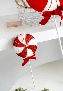 Detail of red and white peppermint candy stick with velvet bow and glitter texture