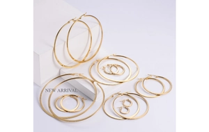 Set of 7 pairs of minimalist golden hoop earrings in various sizes on display stand