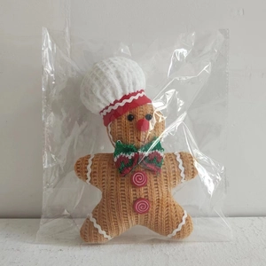 Macro detail of gingerbread man plush pendant with chef hat and red bowtie for Christmas
