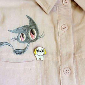 Détail d'une épinglette de chien de dessin animé sur une chemise rose avec broderie chat