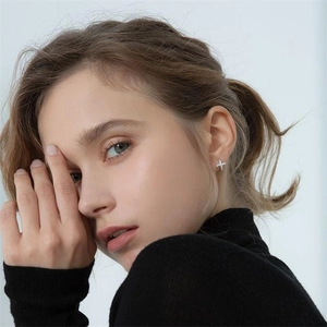 Close-up of S925 sterling silver cross earrings with zircon pavé on model's ear