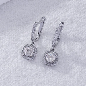 Macro shot of silver drop earrings featuring square halos and brilliant round gemstones