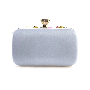 Detail of evening clutch featuring silver satin finish and gemstone clasp for wedding events