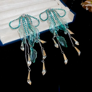Detail of silver bow earrings with turquoise tassels and rhinestones on a display tray