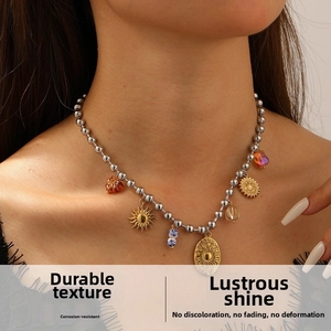 Dettaglio della collana di perline con ciondolo a sole e perle d'ambra sul modello