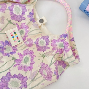 Close-up of floral tote bag with purple cosmos pattern and woven rope handles