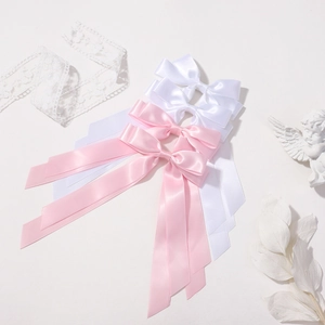 Flat lay of white and pink satin ribbon bow hair clips with long streamers and lace