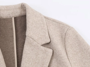 Detailed macro view of soft beige wool blend fabric and premium collar stitching