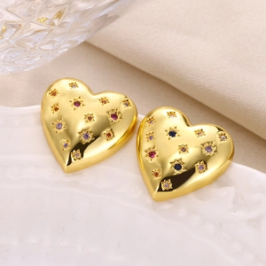 Close-up of golden heart earrings with colorful zircons on white porcelain
