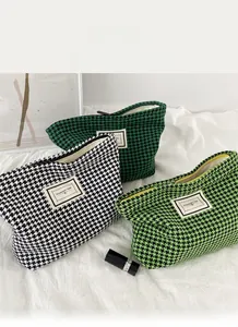Close-up of houndstooth toiletry bags on white fabric with zip closure and fabric label