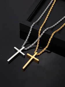 Polished gold and silver stainless steel cross pendants on a sleek black display stand