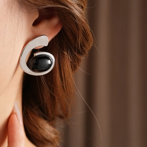 Close-up of a silver geometric earring with a large black oval stone on model