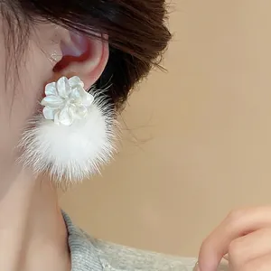Boucles d'oreilles élégantes fleurs blanches et pompons argentés sur modèle