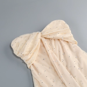 Dettaglio dell'abito da festa senza spalline champagne con perle e paillettes su tulle