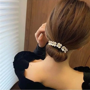Detalle de una pinza para el pelo con cinco flores blancas en un moño bajo