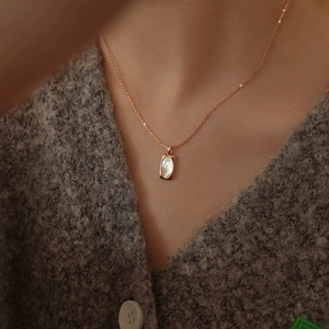Detailed close-up of a rectangular shell pendant necklace on a rose gold chain