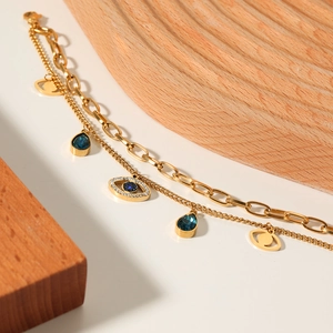 Double-layered gold evil eye bracelet with blue teardrop charms and lobster clasp