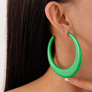 Close-up of model wearing vibrant green oversized C-shaped acrylic hoop earrings