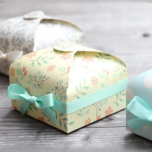 Exquisite vintage floral gift box in beige with a mint green ribbon bow on a wooden desk