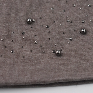 Detailed macro view of brown knit fabric with decorative metallic beads and texture