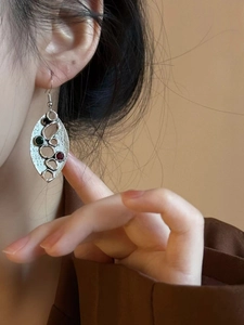 Détail de boucles d'oreilles ovales argentées avec pierres colorées portées