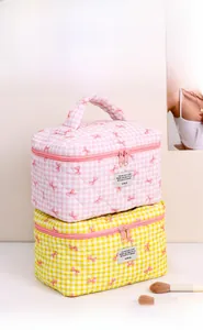Close-up of quilted makeup bags with checkerboard bow patterns and dual zippers