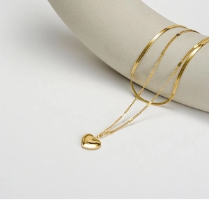 Close-up of golden layered heart necklace featuring double snake and fine link chains