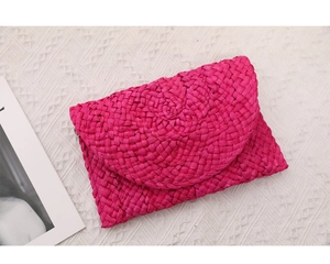 Dettaglio pochette intrecciata a mano color rosso rosa con trama in paglia naturale