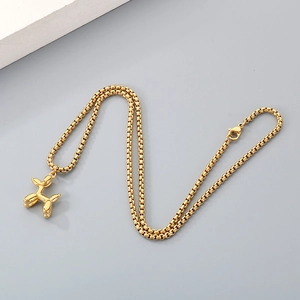 Détail d'un collier doré avec pendentif chien ballon et chaîne à mailles polie