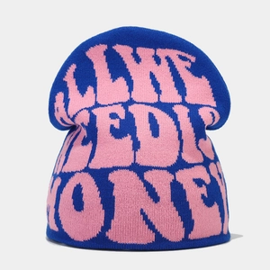 Detail of blue knitted beanie featuring pink jacquard lettering and ribbed texture